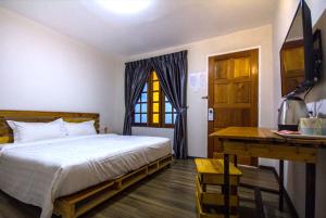 Schlafzimmer mit einem Bett, einem Schreibtisch und einem Fenster in der Unterkunft Kea Garden Guest House in Brinchang