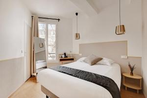 a white bedroom with a bed and a window at Maison Urbaine in Paris