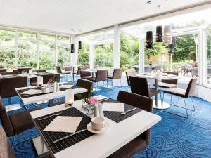 un restaurante con mesas, sillas y ventanas en Novotel Maastricht en Maastricht