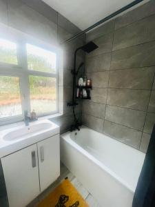 uma casa de banho com uma banheira, um lavatório e uma janela em Cozy bungalow in great location 