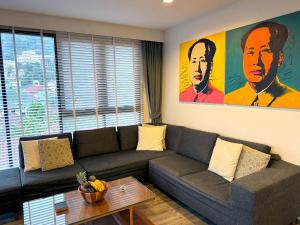 a living room with a couch and a painting on the wall at The Deck Condominium by Lofty in Patong Beach