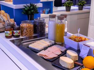 a counter with cheese and other food items on it at ibis budget Epinal in Épinal