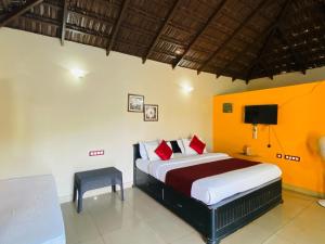 Schlafzimmer mit einem Bett mit roten Kissen und einem TV in der Unterkunft Pool Villa of COORG in Madikeri