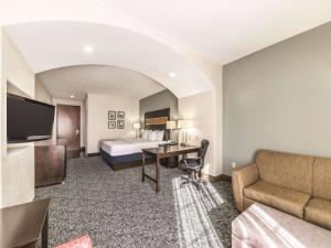 a hotel room with a bed and a couch at La Quinta by Wyndham Tulsa - Catoosa in Catoosa