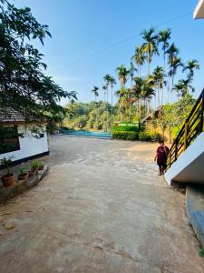 a person walking down a street with palm trees at Pool Villa of COORG in Madikeri