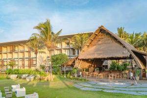 un complejo con un gran edificio con mesas y sillas en Wyndham Tamansari Jivva Resort Bali, en Keramas