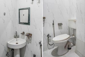 a white bathroom with a toilet and a sink at FabHotel Deepak Palace in Varanasi
