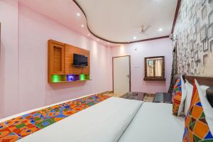a bedroom with a bed and a tv on the wall at FabHotel Deepak Palace in Varanasi