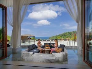 two women sitting on a couch on a patio at Avista Hideaway Phuket Patong - MGallery in Patong Beach