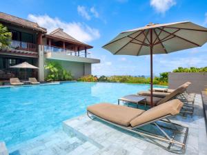 a swimming pool with two lounge chairs and an umbrella at Avista Hideaway Phuket Patong - MGallery in Patong Beach