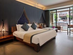 a bedroom with a large bed and a balcony at Avista Hideaway Phuket Patong - MGallery in Patong Beach