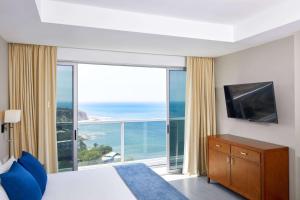 1 dormitorio con ventana grande con vistas al océano en Wyndham Manta Sail Plaza Hotel and Convention Center en Manta