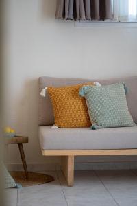 a couch with two pillows on it in a room at Capella Town, Skiathos in Skiathos