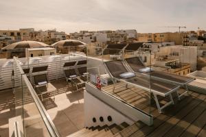 uma varanda com cadeiras e mesas num edifício em The Sliema Suites em Sliema