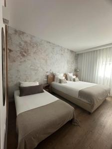 duas camas num quarto de hotel com duas camas sidx sidx em Charm-In Center em Vila Nova de Milfontes