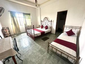 a bedroom with two beds and a table and window at Pearl River Kandy in Kandy