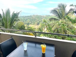 two glasses of orange juice sitting on a table on a balcony at Pearl River Kandy in Kandy