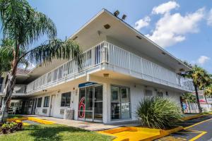 a white building with palm trees in front of it at Motel 6-Jacksonville, FL - Orange Park in Jacksonville