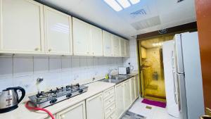 a kitchen with white cabinets and a sink and a refrigerator at PRIVATE FAMILY ROOM BY BJ in Abu Dhabi