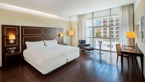 a bedroom with a large white bed and a desk at NH Gran Hotel Casino de Extremadura in Badajoz