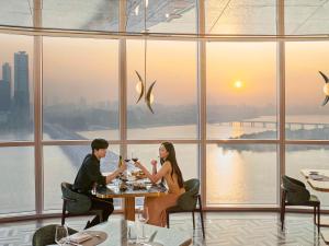 mężczyzna i kobieta siedzący przy stole w restauracji w obiekcie Hotel Naru Seoul MGallery Ambassador w Seulu
