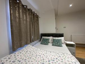 um quarto com uma cama grande e almofadas verdes em Smart Cosy/Small Double Room in Oakridge Road Bromley em Lewisham