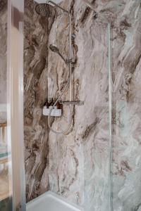 a shower in a bathroom with a marble wall at Our Place In Portland Holiday Home with Sea View in Portland