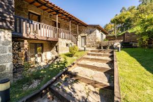 une maison en pierre avec une passerelle à côté d'une cour dans l'établissement Casa do Souto Vieira do Minho - Casa Rural com piscina by House and People, à Vieira do Minho