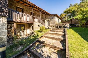 a stone house with a walkway next to a yard at Casa do Souto Vieira do Minho - Casa Rural com piscina by House and People in Lugar