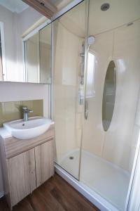 a white bathroom with a sink and a shower at ELVIS, King Of The Caravans, 6 Berth in Port Seton