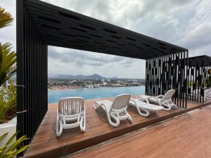 un groupe de chaises sur une terrasse avec piscine dans l'établissement Ipoh Horizon Skypool Town Suites 4-11pax by IWH Suites, à Ipoh