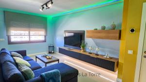 un salon avec un canapé bleu et une télévision dans l'établissement Sup T12 People - Alojamientos La Torre, à Torre del Mar