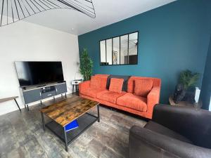a living room with an orange couch and a tv at Appart XXL -10 pers - 2 Pkg - 10 mn Paris in Épinay-sur-Seine