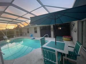 uma piscina com uma mesa e um guarda-sol em Guest house withl kitchen living room 65" tv solar heated pool em Palm Coast