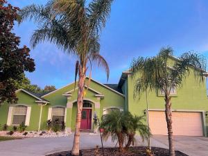 uma casa verde com palmeiras em frente em Guest house withl kitchen living room 65" tv solar heated pool em Palm Coast