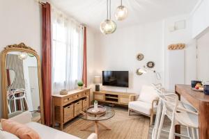 ein Wohnzimmer mit einem TV, einem Tisch und Stühlen in der Unterkunft L46 2P Port, 2min du Cap et 5 du port/ CLIM & WIFI in Nizza