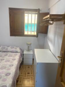 Habitación pequeña con cama, lavabo y ventana en Primera línea de playa, en Valencia