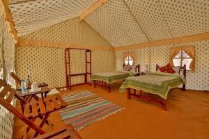 an attic room with two beds and a table at Atithi Camp & Resort in Pushkar