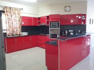 a red kitchen with red cabinets and a clock at Heaven Heights - Fully Furnished Air Con Apartment in Rose Hill