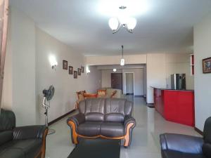 a living room with a leather couch and a kitchen at Heaven Heights - Fully Furnished Air Con Apartment in Rose Hill