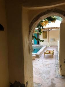 un arco in una casa con piscina e tavolo di Dar Kenza a Djerba