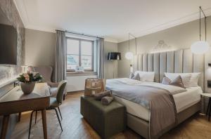1 dormitorio con 1 cama grande, 1 silla y 1 mesa en Romantik Spa Hotel Elixhauser Wirt en Elixhausen