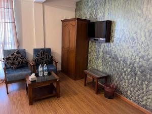 een woonkamer met 2 stoelen en een tv aan de muur bij Hotel Pokhara View backup in Pokhara