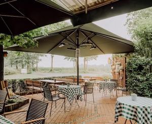 une terrasse avec des tables et des chaises sous un parasol dans l'établissement Auehof Hotel & Restaurant, à Garrel