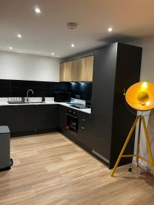 uma cozinha com armários pretos e uma mesa amarela em Modern and spacious two bedroom apartment near city centre em Bristol