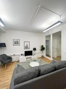 ein Wohnzimmer mit einem Sofa und einem TV in der Unterkunft Kotimaailma Apartments Kamppi - 1BR with a key code in Helsinki