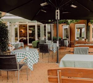 d'une terrasse avec des tables, des chaises et un parasol. dans l'établissement Auehof Hotel & Restaurant, à Garrel