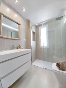 a white bathroom with a shower and a sink at Royal Blue Corralejo by Sea You There Fuerteventura in Corralejo