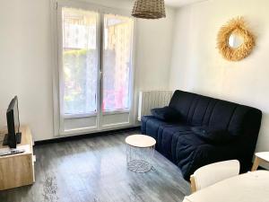 a living room with a blue couch and a window at T2 jardinet, accès direct plage in Cabourg