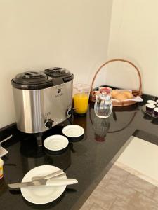 eine Arbeitsplatte mit einer Kaffeemaschine, Tellern und Orangensaft in der Unterkunft Hotel E Flats LISBOA in Presidente Médici